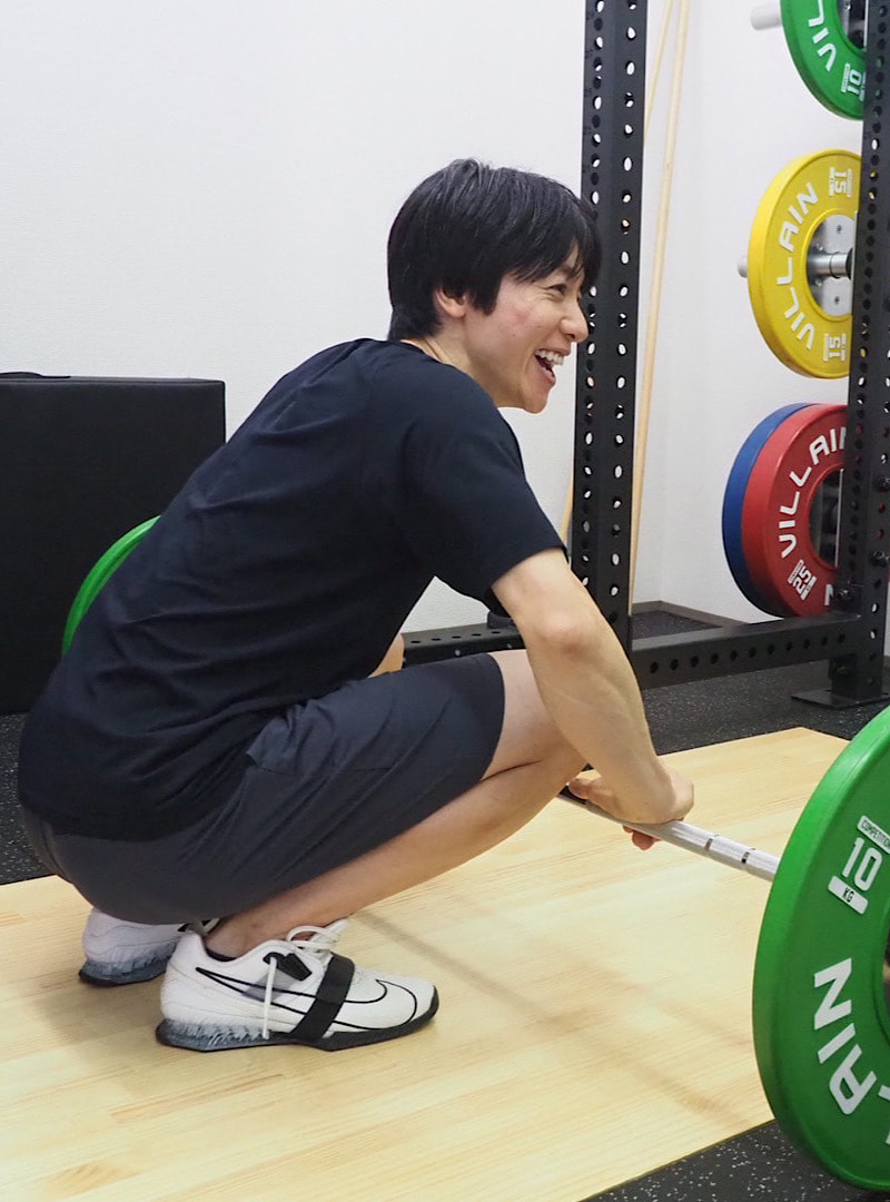 笑顔でウエイトトレーニングの準備をする代表トレーナー