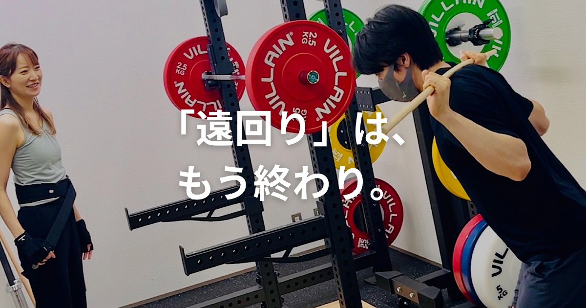 パーソナルトレーナーからバーベルスクワットの指導を受ける女性
