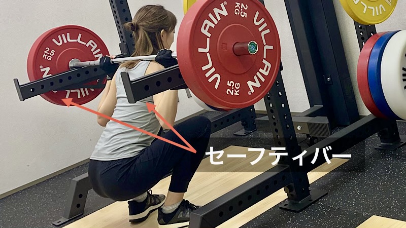 スクワットをしている女性と、安全のためのセーフティバー