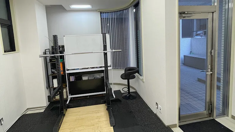 港区赤坂のバーベルトレーニング専門ジム「TAKASE GYM」の店内。スクワットラックにバーベルが設置されていて、床にはプラットフォームが完備されている。日当りの良い清潔なプライベート空間になっている。