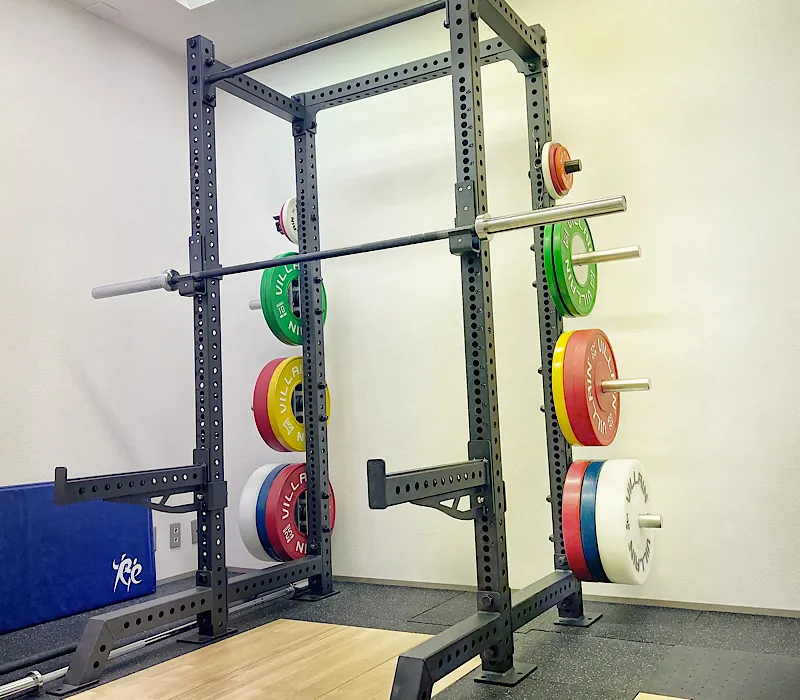 本格的なトレーニングが可能なハーフラック。バーベルと色分けされたウェイトプレート、専用のプラットフォームが完備されたトレーニングエリア。