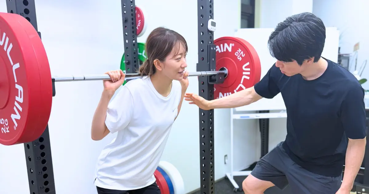 女性にスクワットの指導をしているTAKASE GYMのトレーナー